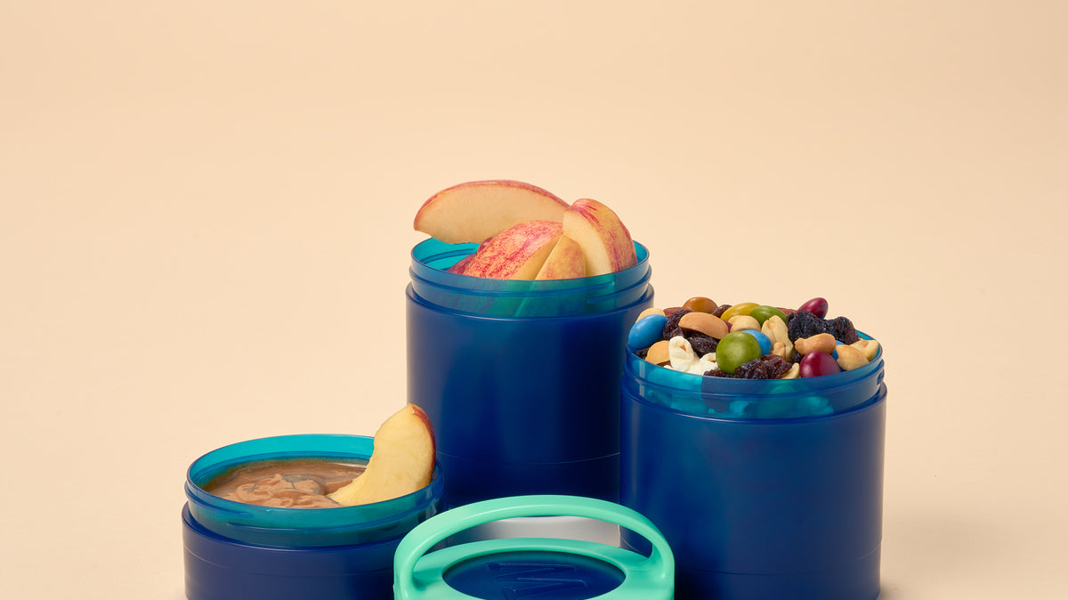 A blue Whiskware Snack Container filled with healthy snacks on a plain white background.