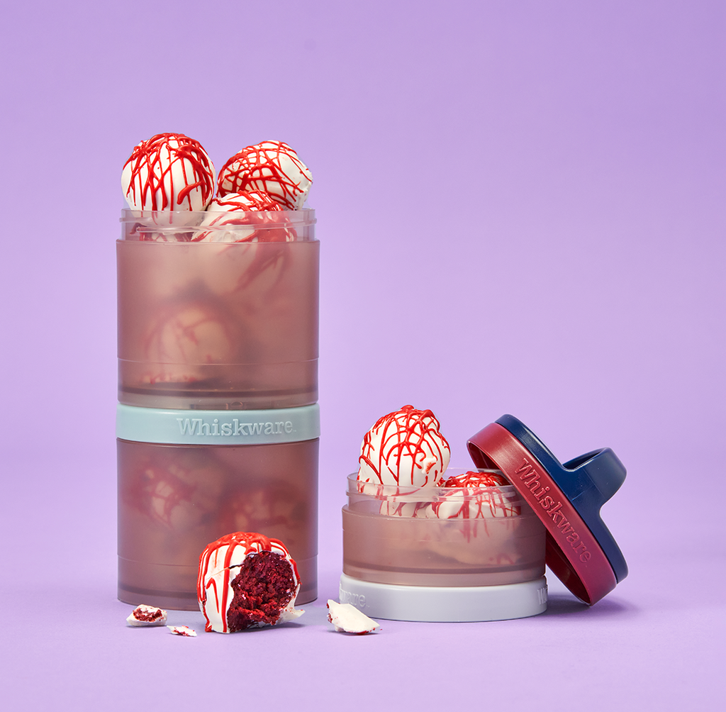 A whiskware snacking container with the top jar removed and filled with cake balls coated in white icing and drizzled with red to look like blood splatter.