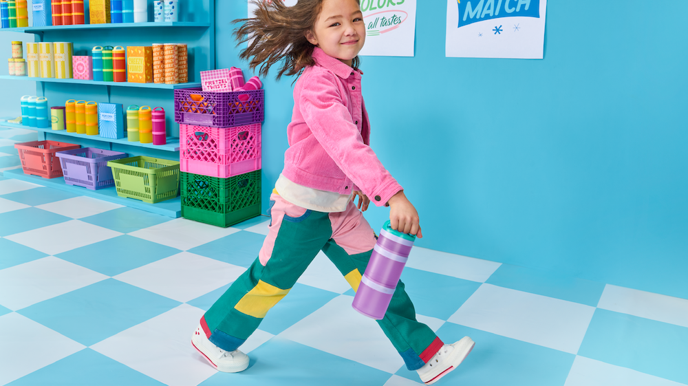 Girl walking in a colorful snack store carrying a Whiskware snack container