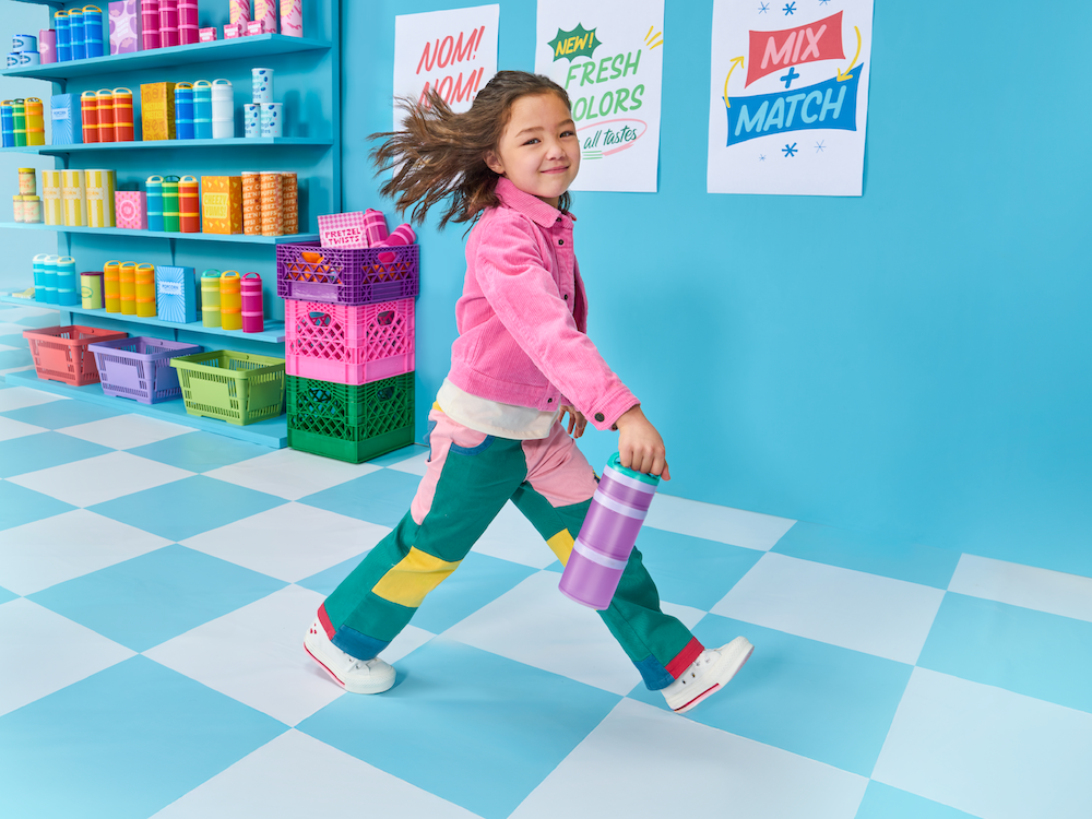 Girl walking in a colorful snack store carrying a Whiskware snack container