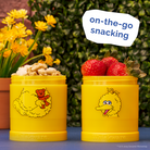 Yellow snack container filled with granola and strawberries in front of an outdoor garden background.