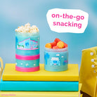 Colorful snack containers with snacks on a blue background, featuring the text 'on-the-go snacking'.