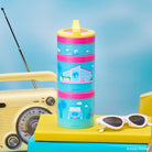 Stackable Barbie snack container with pink lids and blue cups on a blue background, featuring a vintage radio and sunglasses.